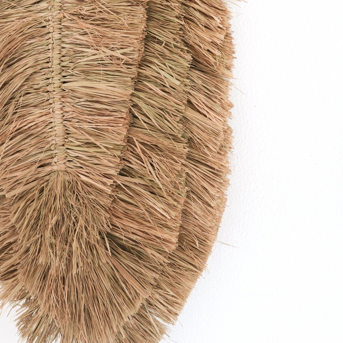 Wanddecoratie van handgeweven raffia ingezoomd op de onderkant