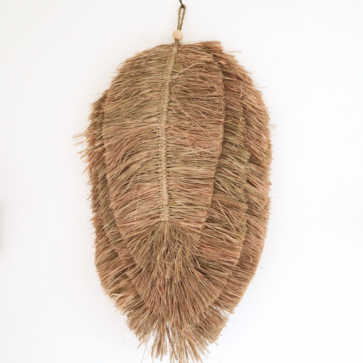 Wandhanger van handgeweven raffia op een witte muur