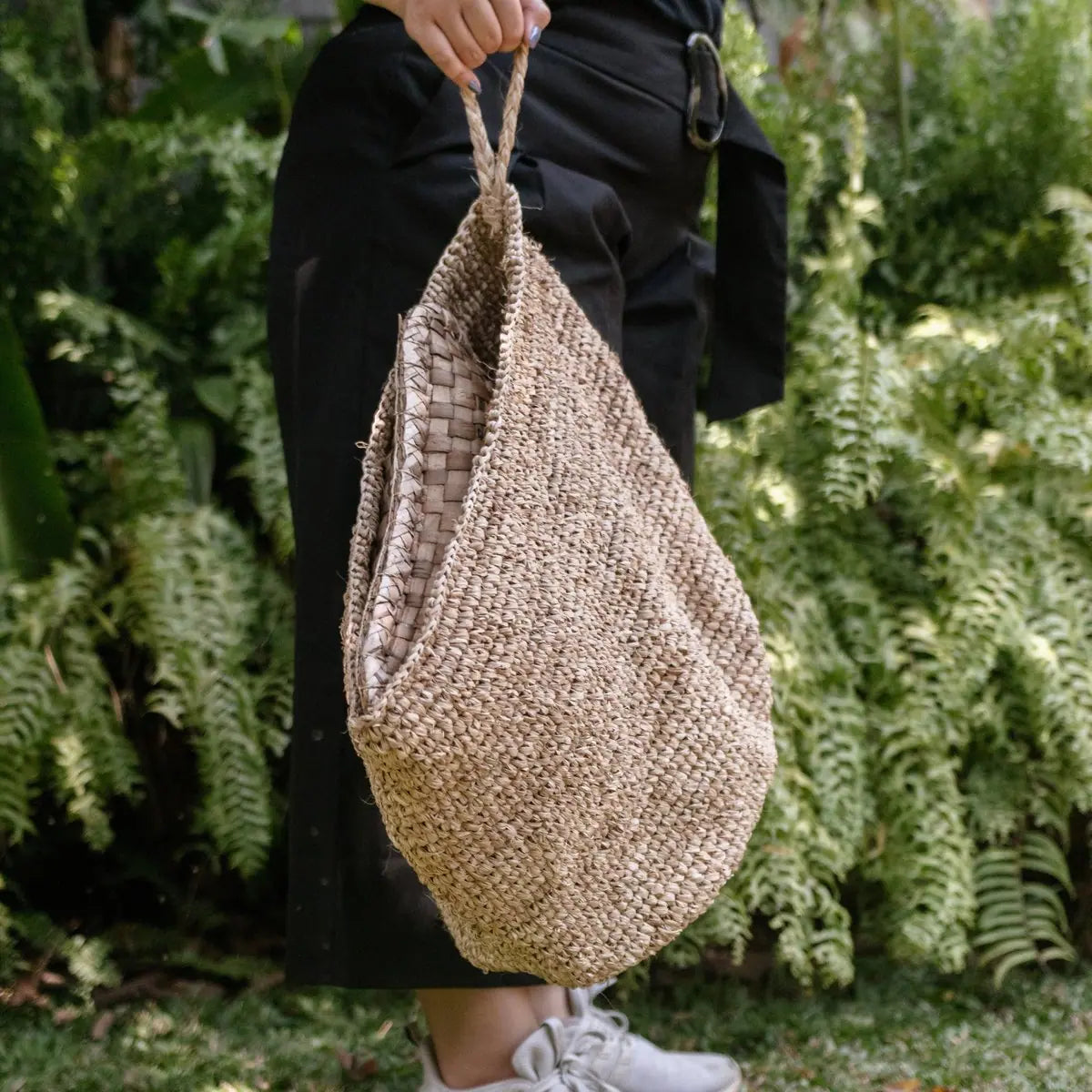 Wandmand van raffia vastgehouden door een vrouw