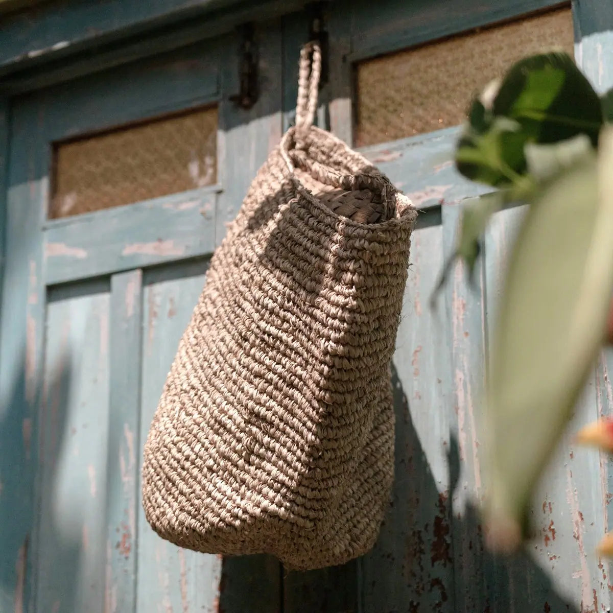 Wandmand van raffia hangend aan haak aan de muur