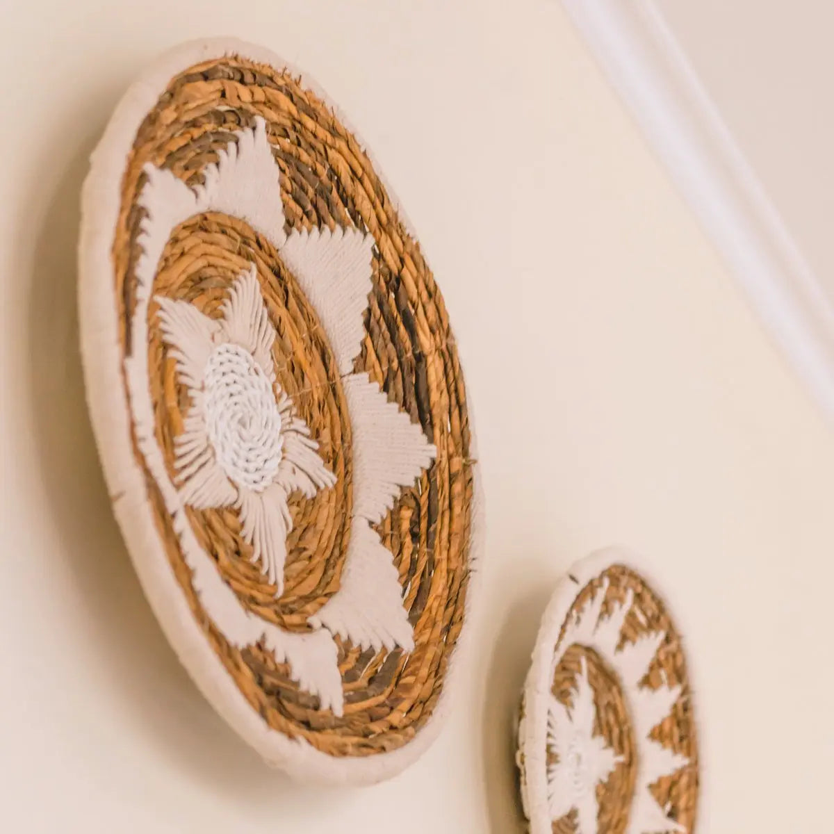 Twee wandschalen van bananenvezel aan de muur hangend schuin van onder gezien