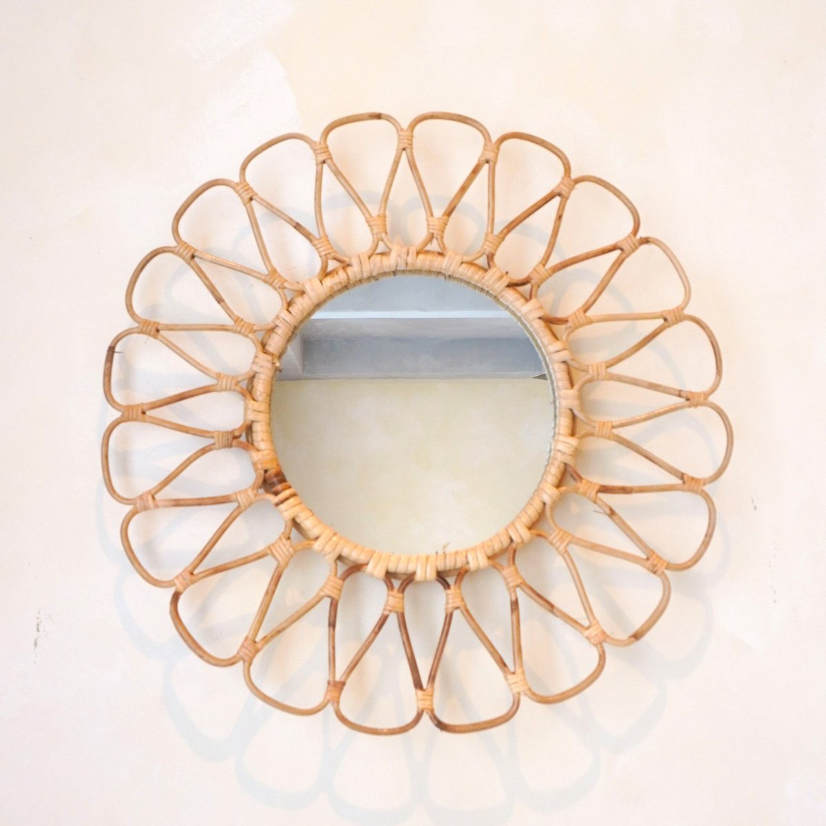 Wandspiegel van rotan op een beige muur