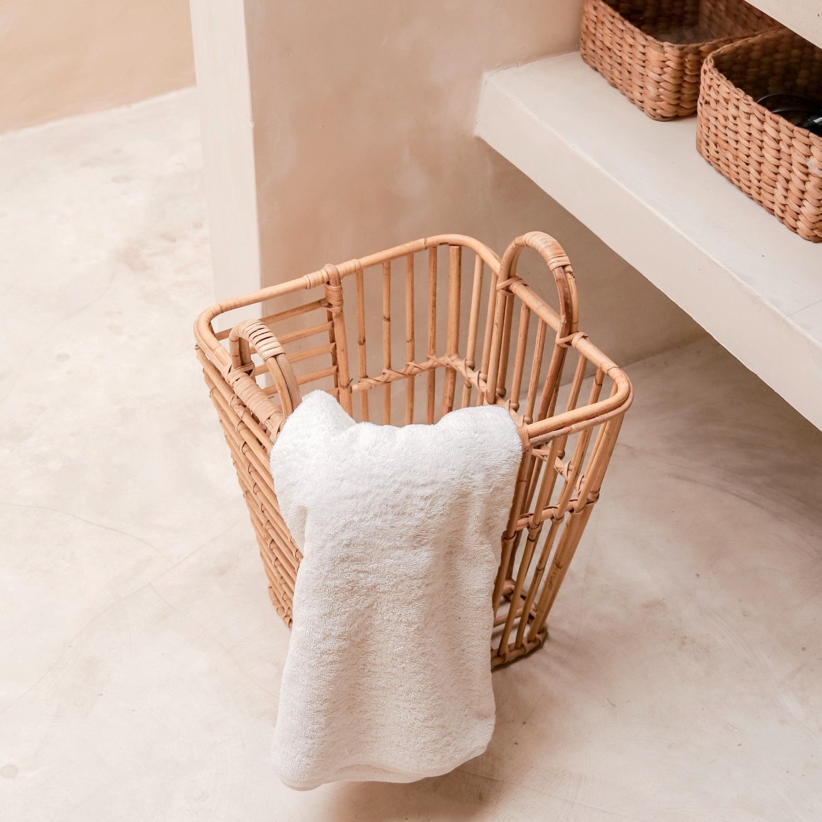 Wasmand van rotan met een handdoek erin staand in de badkamer
