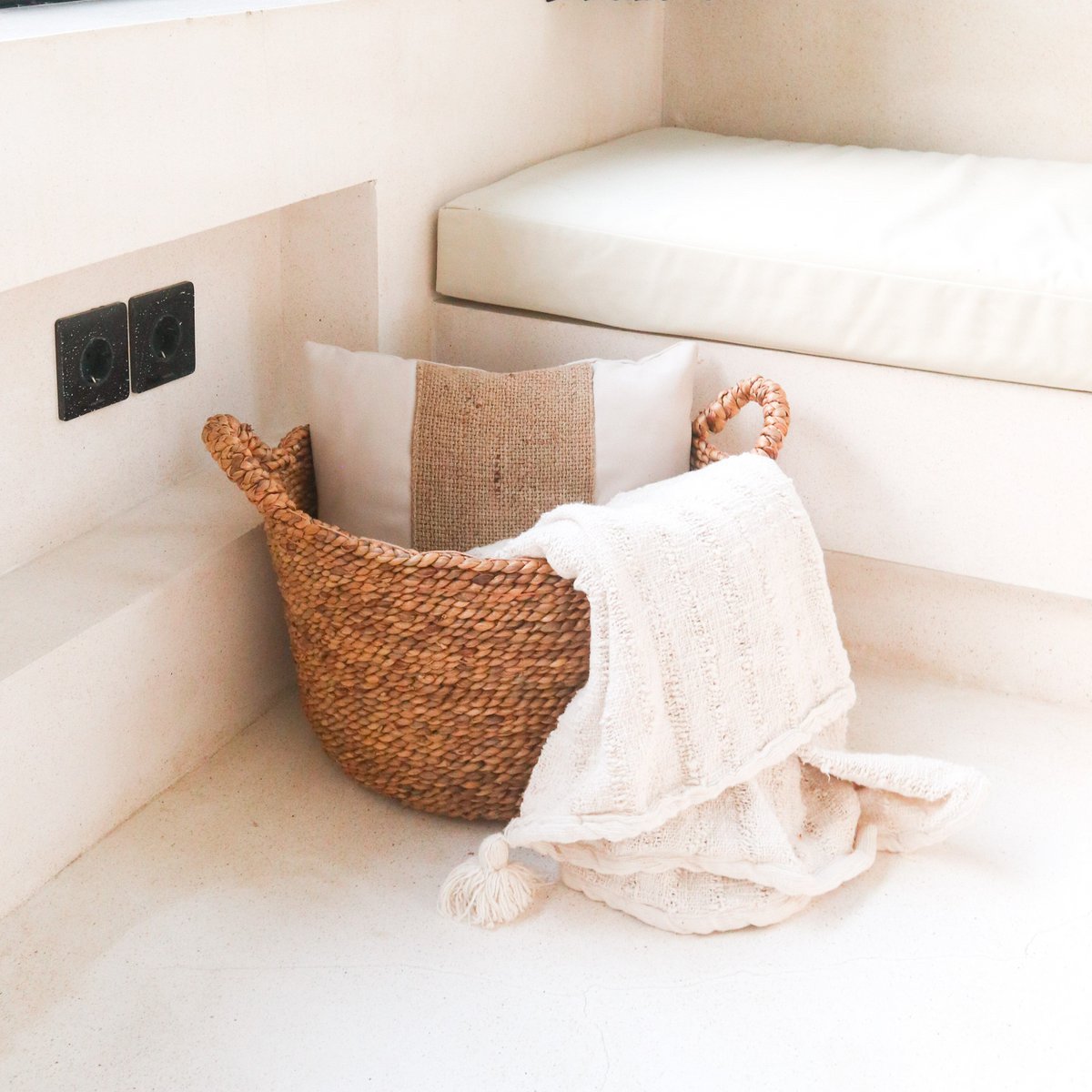 Wasmand van waterhyacint met een kussen en handdoek erin