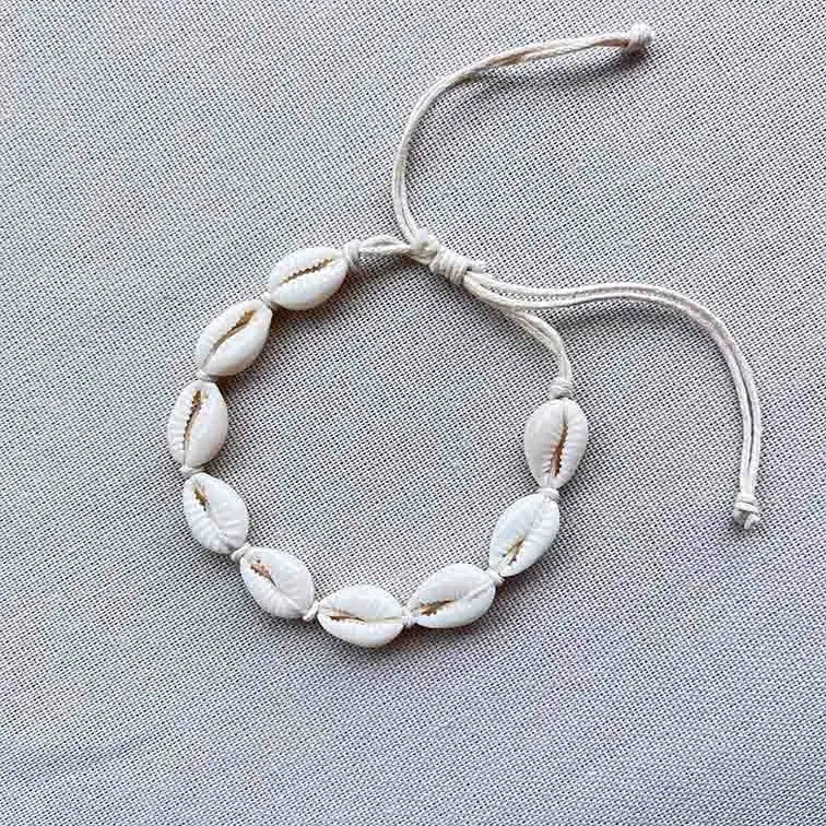 Armbandje met kauri schelpjes op een zijden doek