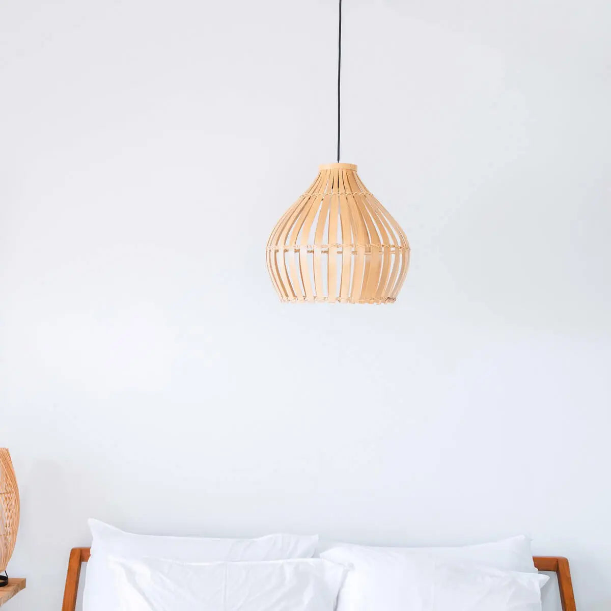 Bamboe lampenkap hangend boven een bed voor een witte muur