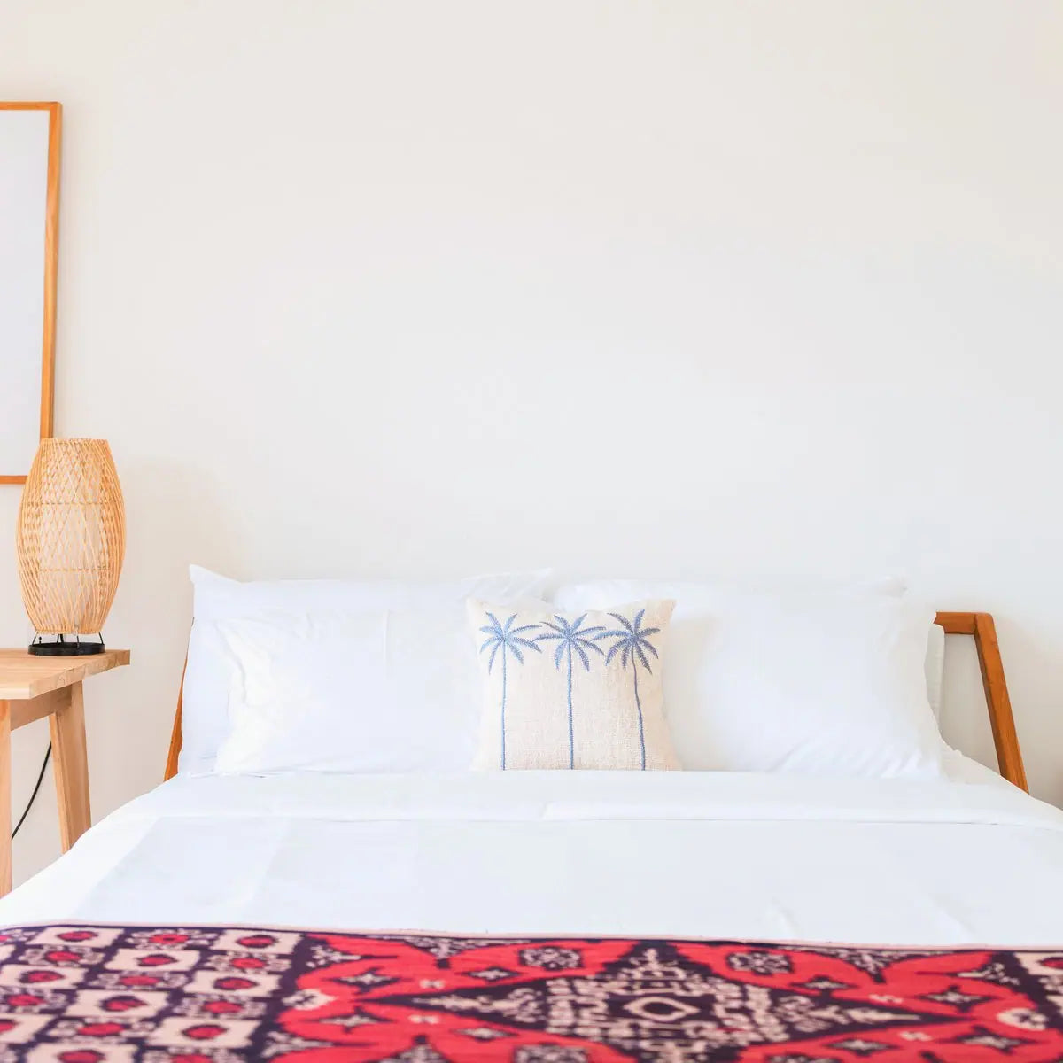 Katoenen kussenhoes met drie palmbomen erop op een bed