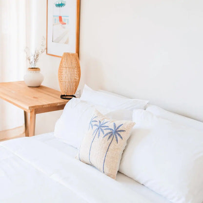 Katoenen kussenhoes met daarop drie palmbomen op een bed 