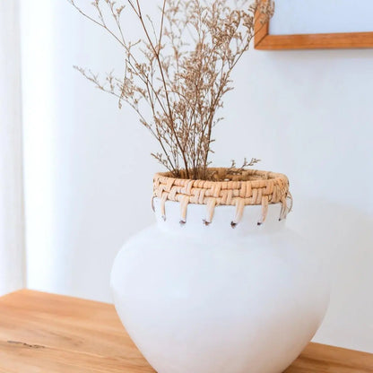 Witte vaas van klei met daarin droogbloemen staand op tafel