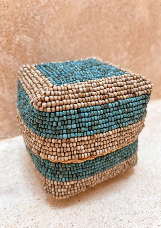 Offermandje staand op de grond voor een muur