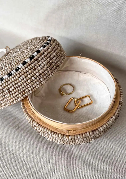 Rond offermandje met sieraden erin op een zijden doek