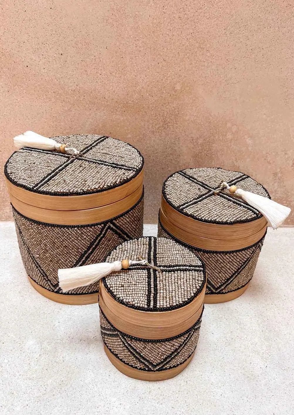 Drie offermandjes, klein, middel en groot met een mix van bruine, zwarte en zilveren kleuren voor een bruine muur vanaf schuin boven gezien