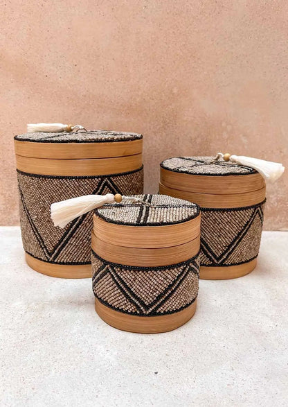 Drie offermandjes, klein, middel en groot met een mix van bruine, zwarte en zilveren kleuren op de grond voor een bruine muur