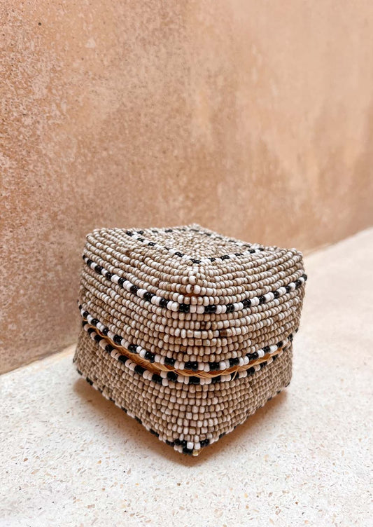 Offermandje staand op de grond voor een muur