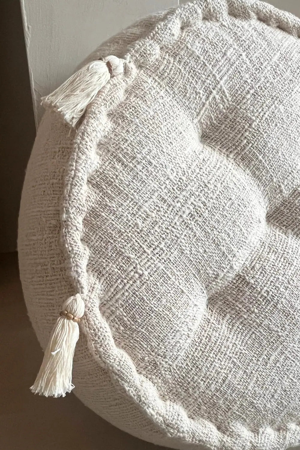 Ronde poef in creme kleur met franjes schuin van dichtbij gezien