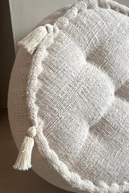 Ronde poef in creme kleur met franjes schuin van dichtbij gezien