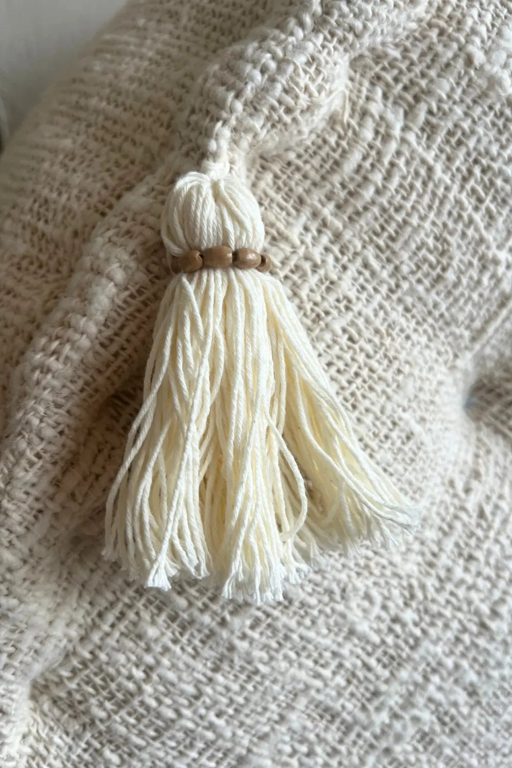 De franje van een  poef van katoen in creme kleur van dichtbij gezien