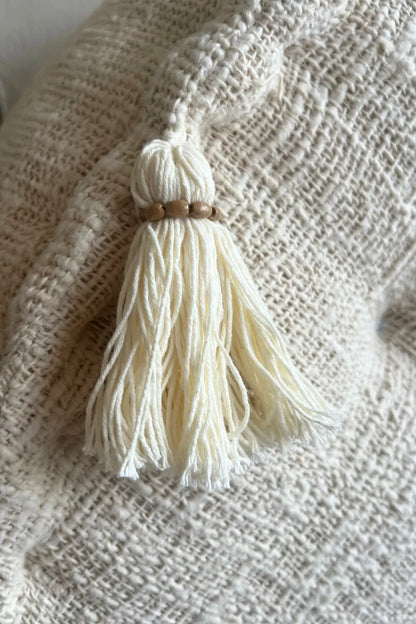 De franje van een  poef van katoen in creme kleur van dichtbij gezien