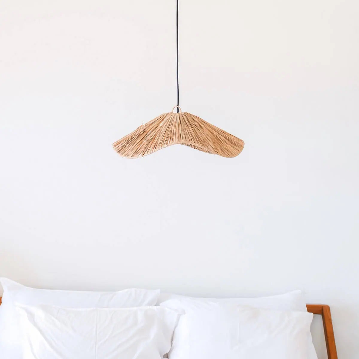 Raffia lampenkap hangend boven een bed