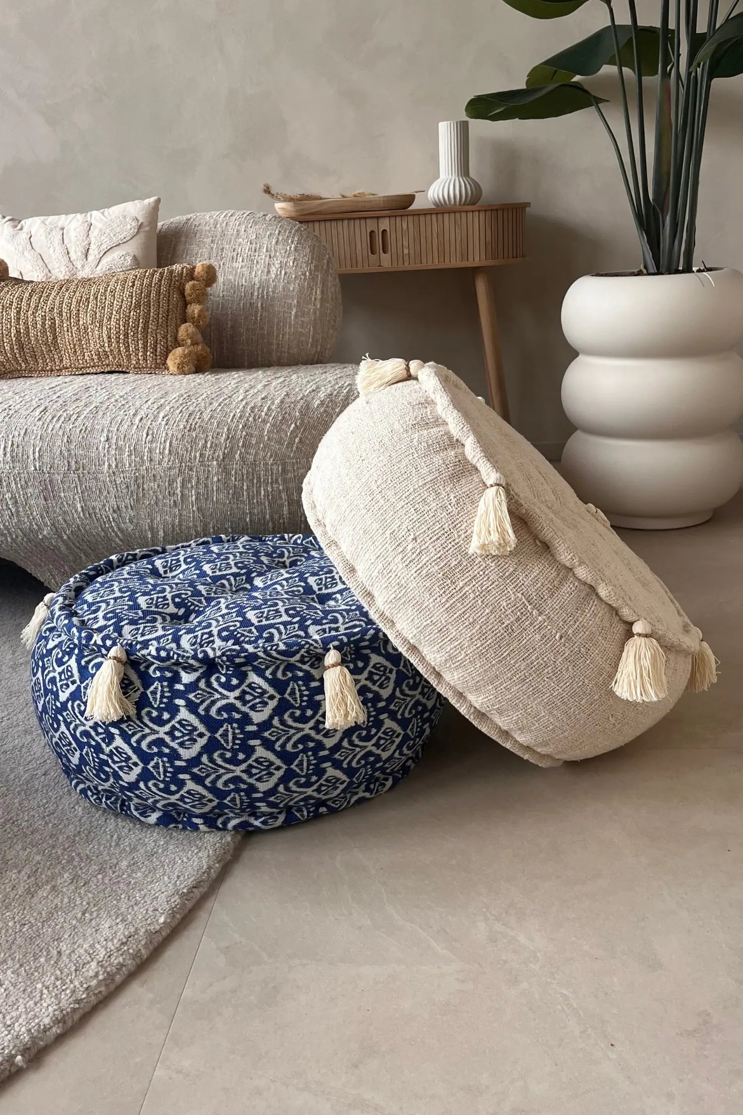 Twee ronde poefen oin blauw-witte kleur en crème kleur schuin boven op elkaar gelegd