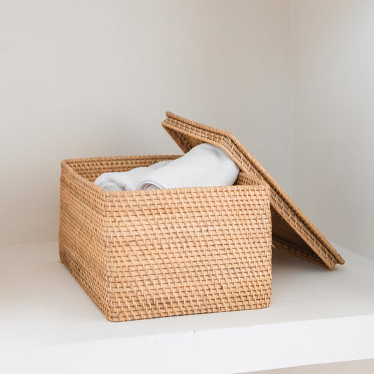 Rotan opbergmand met open deksel en witte handdoeken erin