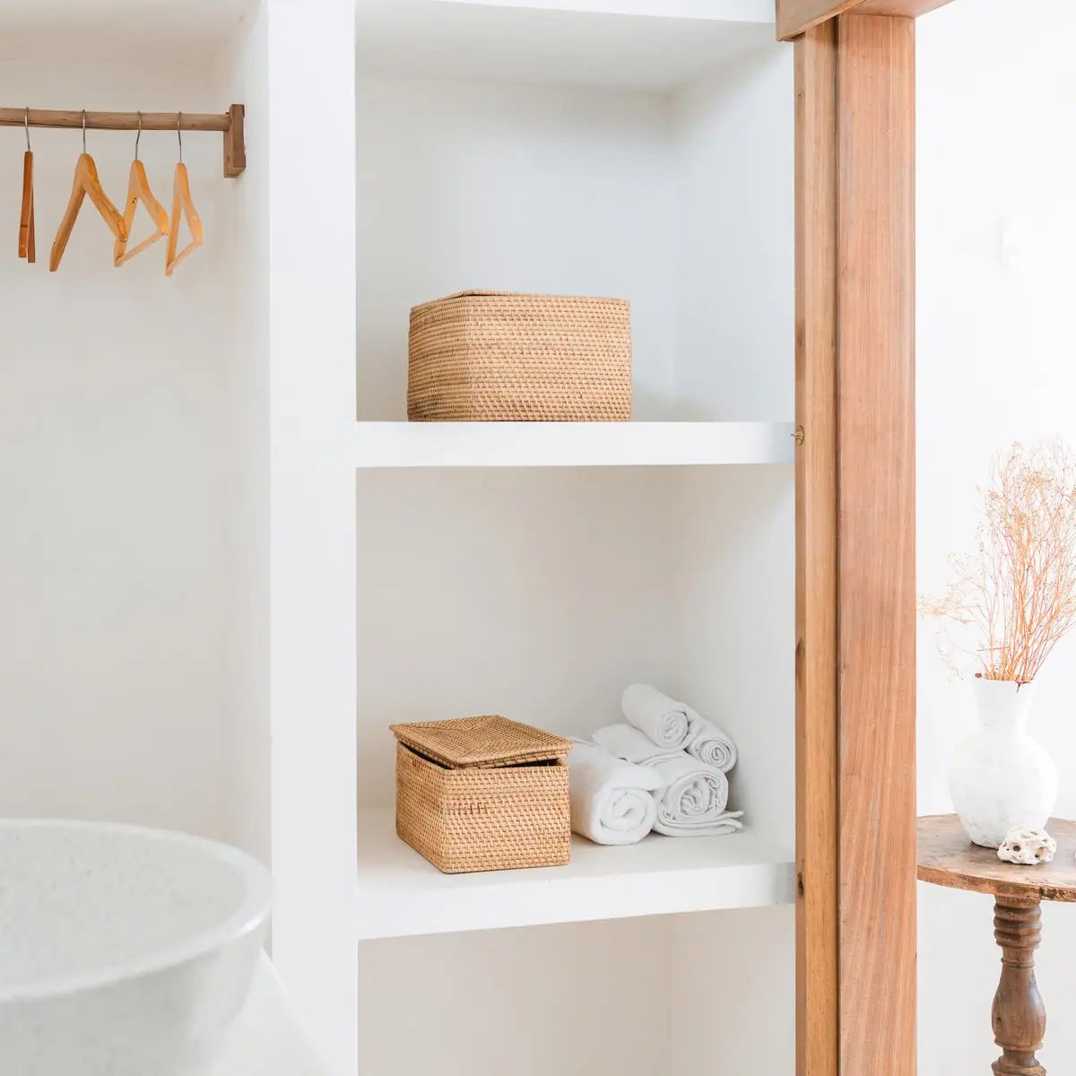 Twee rotan opbergmanden in witte nis naast badkameraccessoires