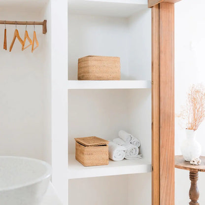 Twee rotan opbergmanden in witte nis naast badkameraccessoires