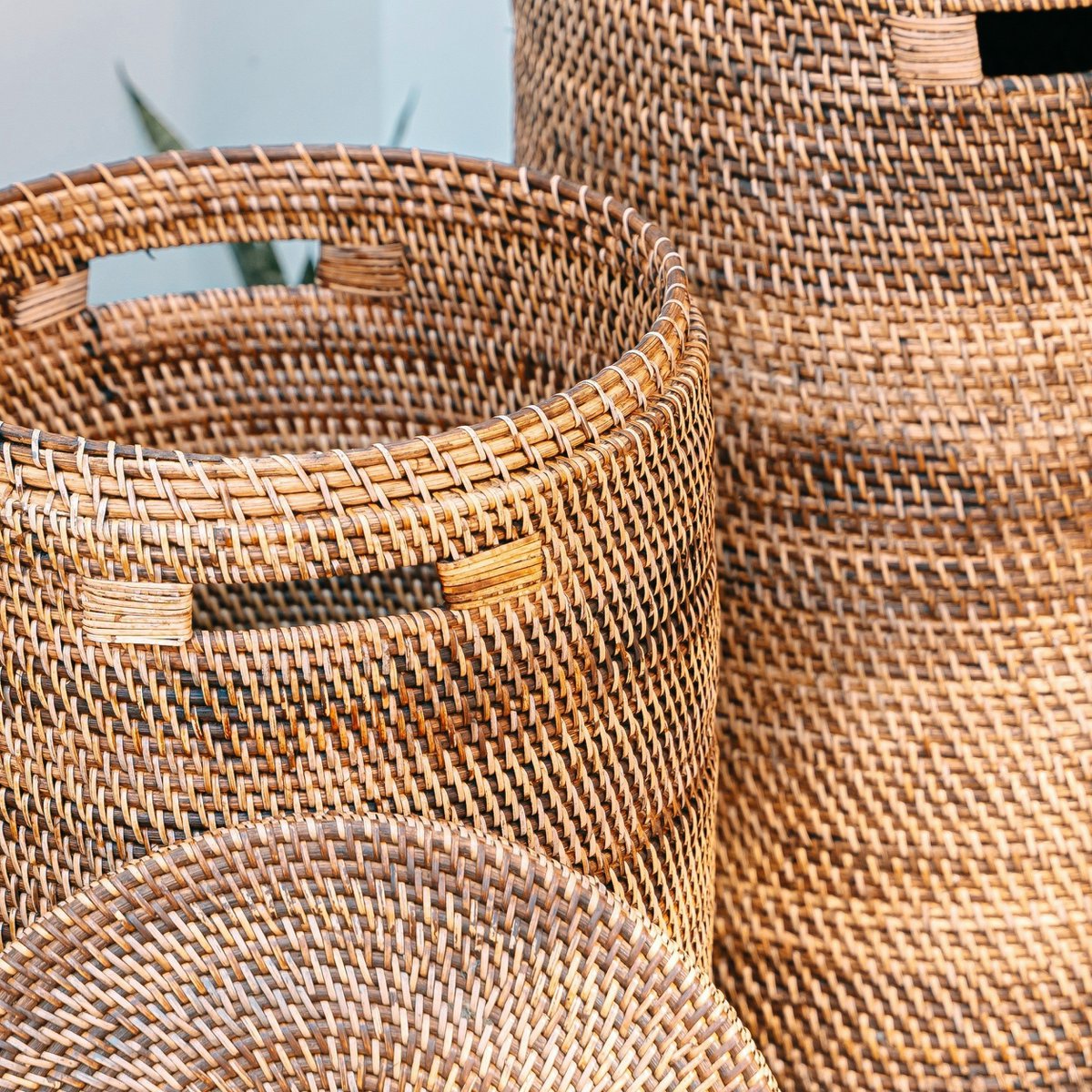 Twee rotan wasmanden buiten, één met open deksel zodat het interieur zichtbaar is.