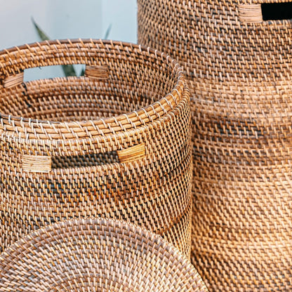 Twee rotan wasmanden buiten, één met open deksel zodat het interieur zichtbaar is.