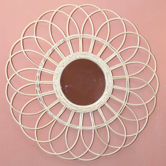 Spiegel van rotan op een roze muur