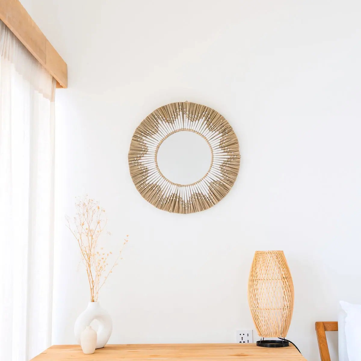 Ronde spiegel van zeegras aan een witte muur boven een bureau