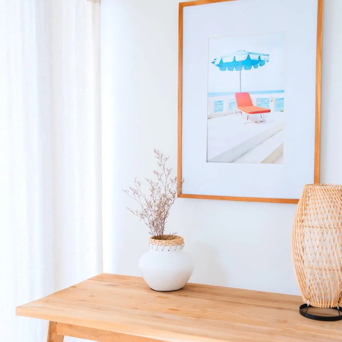 Witte boho vaas van klei met daarin een droogbloem op een tafel