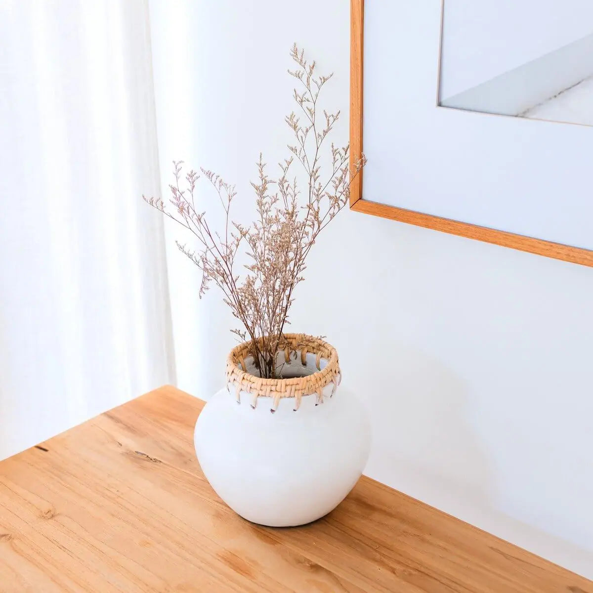 Witte vaas van klei met een droogbloem erin op tafel