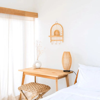 Wandrek van rotan met haken hangend aan een witte muur boven een tafel