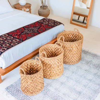 Drie waterhyacint manden van verschillende maten achter een bed