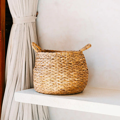 Ronde waterhyacint mand staand op een plank naast een gordijn