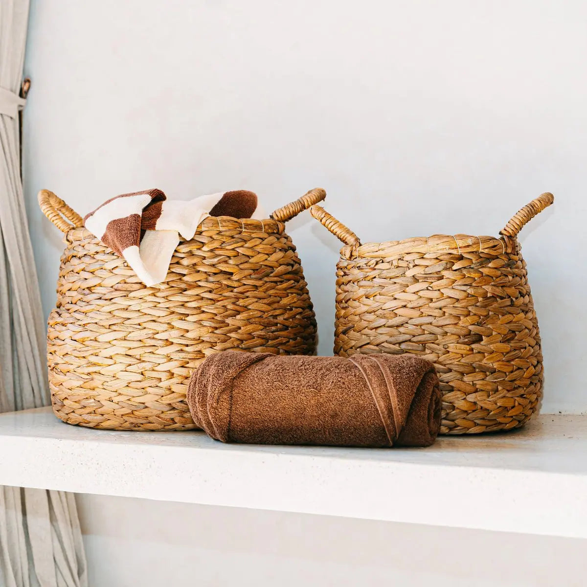 Twee gevlochten waterhyacint wasmanden met daarin een handdoek